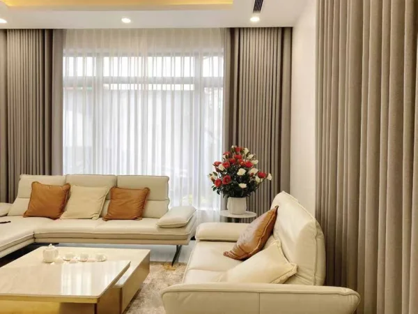 Phòng khách với rèm vải hai lớp màu be và rèm voan phủ kín mảng kính lớn